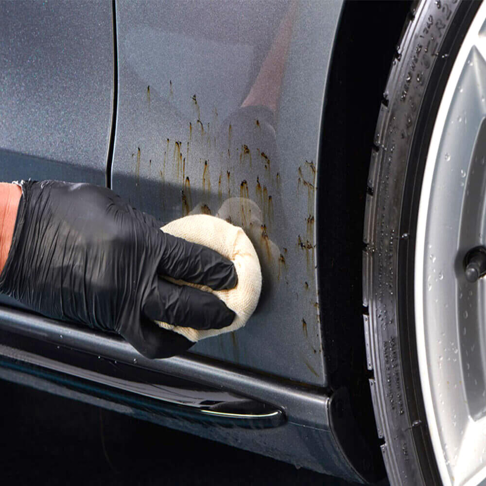 hand wiping tar from car body using tar remover